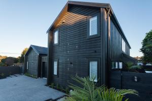 ein schwarzes Haus mit einem Holzdach in der Unterkunft Paradise Beach 3 Bedroom Luxury Accommodation in Papamoa
