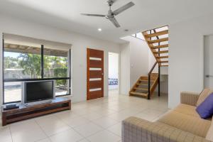 a living room with a television and a staircase at Rainbow Surf 5 in Rainbow Beach