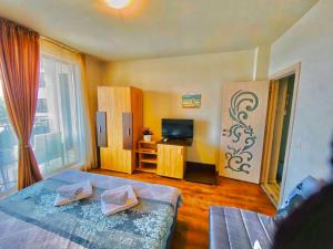 a bedroom with a bed and a tv and a window at DIAMOND APARTMENT №1 - RELAX HOLIDAY VIEWS SEA AND POOL in Burgas City