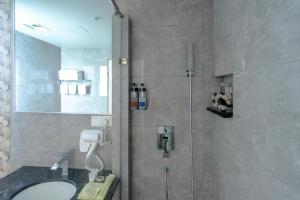 a bathroom with a shower with a sink and a mirror at Arena Beach Hotel in Maafushi