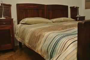 łóżko w sypialni z drewnianym zagłówkiem w obiekcie Studio Errepì Loreto w Mediolanie