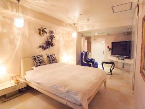 um quarto com uma grande cama branca e uma televisão em V Hotel (Adult Only) em Kobe