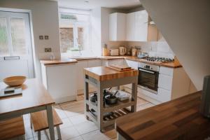 uma cozinha com armários brancos e uma mesa com panelas e frigideiras em Marina View cottage em Furness Vale