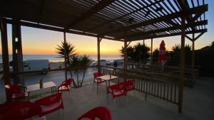 un ristorante con sedie rosse, tavoli e l'oceano di Rock´s Beach Spot a Costa da Caparica