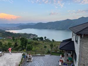 a woman standing on a balcony looking at a lake at The North Face Inn's Homestay in Pokhara