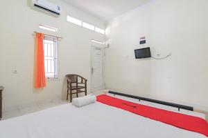 - une chambre avec un lit et une télévision murale dans l'établissement RedDoorz Syariah near Tugu Pandanwangi Cianjur, 