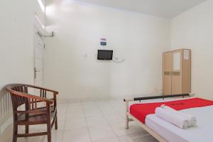 a room with a bed and a chair in it at RedDoorz Syariah near Tugu Pandanwangi Cianjur in Cibulakan +9 photos