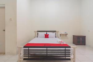 - une chambre avec un lit et un oreiller rouge dans l'établissement RedDoorz Syariah near Tugu Pandanwangi Cianjur, 