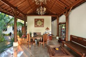 a dining room with a table and chairs and a chandelier at The Kampung Ubud Villa in Ubud