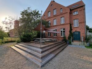 einem Picknicktisch mit einem Regenschirm vor einem Backsteingebäude in der Unterkunft An Den Wiesen Gasthaus am Finowkanal in Wandlitz