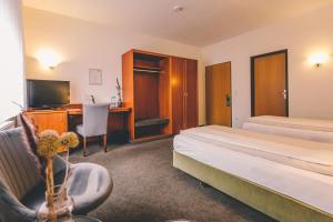 a hotel room with two beds and a desk at Hotel Gasthaus Appel Krug in Delbrück