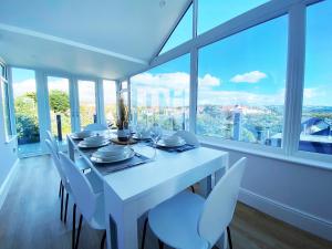 a white dining room with a white table and chairs at The Old Tywyn Post Office in Conwy