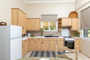 eine Küche mit Holzschränken und einem weißen Kühlschrank in der Unterkunft Πλήρως ανακαινισμένη μονοκατοικία. in Chania