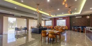 een restaurant met houten tafels, stoelen en ramen bij The Aanandam Hotel Resort in Itārsi