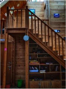 een houten trap met een klok aan een muur bij The Door to Nirvana Backpackers Hostel Kotagiri in Kotagiri