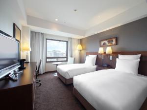 Habitación de hotel con 2 camas y TV de pantalla plana. en Okinawa Harborview Hotel, en Naha