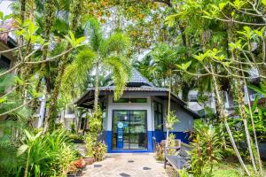 a house with a blue door in the middle of trees at Kokotel Khao Lak Lighthouse in Khao Lak