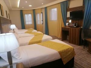 a hotel room with four beds and a television at فندق الميقات أجياد in Mecca