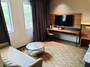 ジョホールバルにあるNB HOTELのソファ、デスク、テレビが備わるホテルルームです。