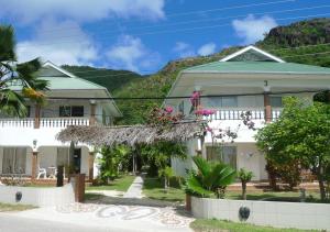a white house with a mountain in the background at Villa Anse Possession in Baie Sainte Anne