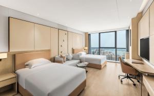 Habitación de hotel con 2 camas, escritorio y TV. en Crowne Plaza Changsha Development Zone, an IHG Hotel en Xingsha
