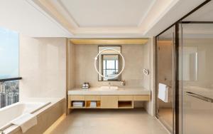 Crowne Plaza Changsha Development Zone, an IHG Hotel في Xingsha: حمام مع حوض وحوض ومرآة