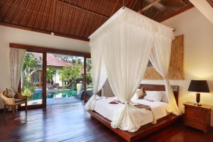 ein Schlafzimmer mit einem Himmelbett und einem Pool in der Unterkunft The Kampung Ubud Villa in Ubud