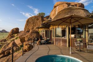 a resort with a swimming pool and an umbrella at Camp Kipwe in Twyfelfontein