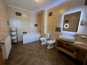 a bathroom with a tub and a toilet and a sink at Pensiunea Violeta in Saschiz