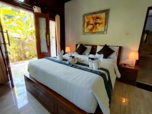 a bedroom with a large white bed with rabbits on it at Exotic View Cottage in Nusa Penida