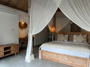 1 dormitorio con cama con dosel y cortinas en Santana Villas Bingin, en Uluwatu