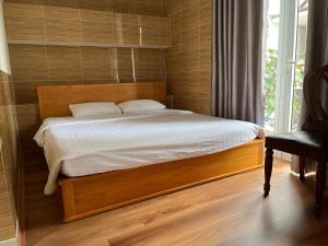 um quarto com uma cama com uma moldura de madeira e uma janela em Hostel Phuong Nga em Da Lat
