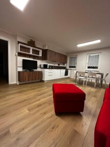 an empty living room with a red chair and a table at Trentino Apartments - Casa Laita in Folgaria