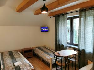 een kamer met twee bedden, een tafel en een raam bij Willa CIS in Karpacz