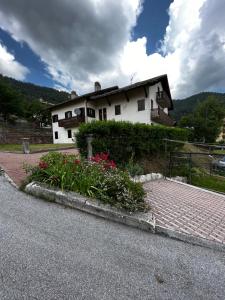 a white house with flowers on the side of the road at Trentino Apartments - Casa Laita in Folgaria