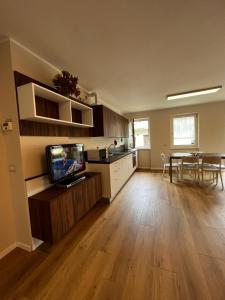 eine Küche und ein Wohnzimmer mit einem TV und einem Tisch in der Unterkunft Trentino Apartments - Casa Laita in Folgaria