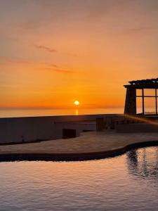 una puesta de sol sobre un cuerpo de agua con un faro en Casa das Rosas en Carvoeira