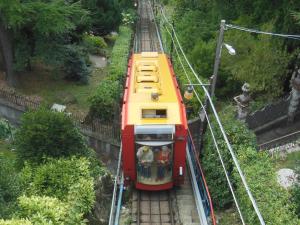 a red and yellow train traveling down the tracks at B&B Villa Mirandola in Brunate