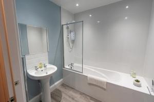 ein weißes Bad mit einem Waschbecken und einer Dusche in der Unterkunft Daffodil House in Cockermouth