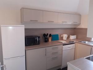 a kitchen with white cabinets and a black microwave at Carvetii - Laurel House - 2 bed House sleeps up to 8 