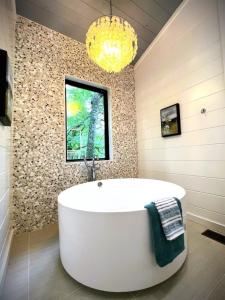 布罗肯鲍Key West Cottage的一个带吊灯的浴室内的一个大型白色浴缸