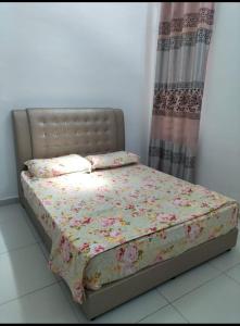 a bed with a floral comforter and pillows on it at Noorsyah Homestay Stadium Utama in Kangar