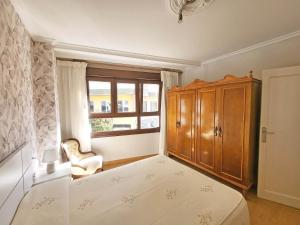um quarto com uma cama, um armário e uma janela em Apartamentos Portonovo 3000 em Portonovo