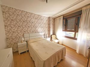 um quarto com uma cama, uma cadeira e uma janela em Apartamentos Portonovo 3000 em Portonovo