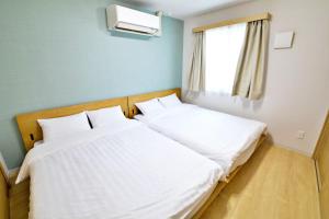 two beds in a small room with a window at メイスン倶楽部 安里 4F in Naha