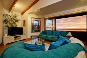 uma sala de estar com um sofá verde e uma televisão em A Room With a View em Kaikoura