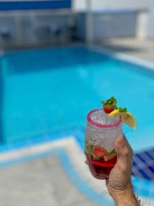 a person holding a drink in front of a pool at Imperial Suites Hotel in Doha