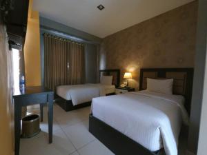 Una habitación de hotel con dos camas y un televisor. en Anaya Hotel and Ballroom, en Medan