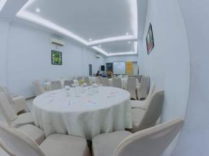 メダンにあるAnaya Hotel and Ballroomの白いテーブルと白い椅子が備わる客室です。