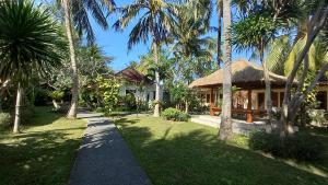 a resort with a pathway leading to a building with palm trees at Segara Anak Hotel in Kuta Lombok